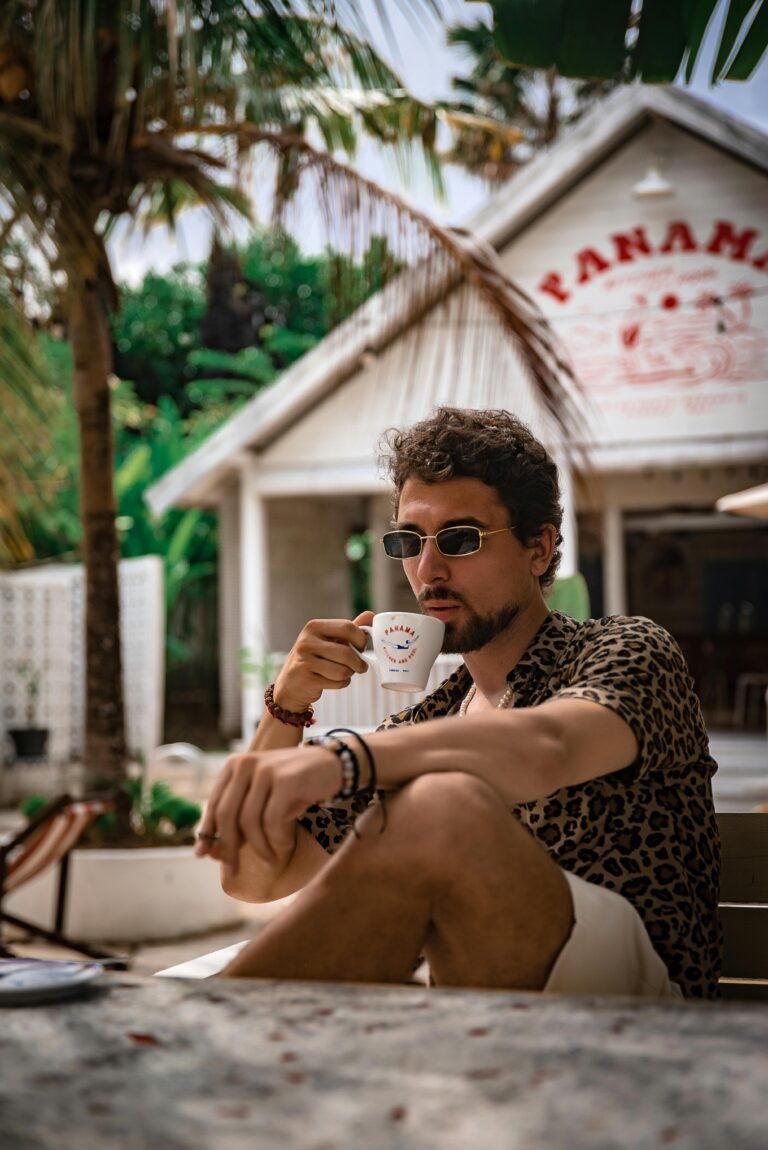 Chico guapo tomando café en Panamá Horizon Ecuador | Viajes personalizados y experiencias únicas - hombre joven vestido con una camisa atigrada Shorts pulseras tomando una taza de café en Panamá
